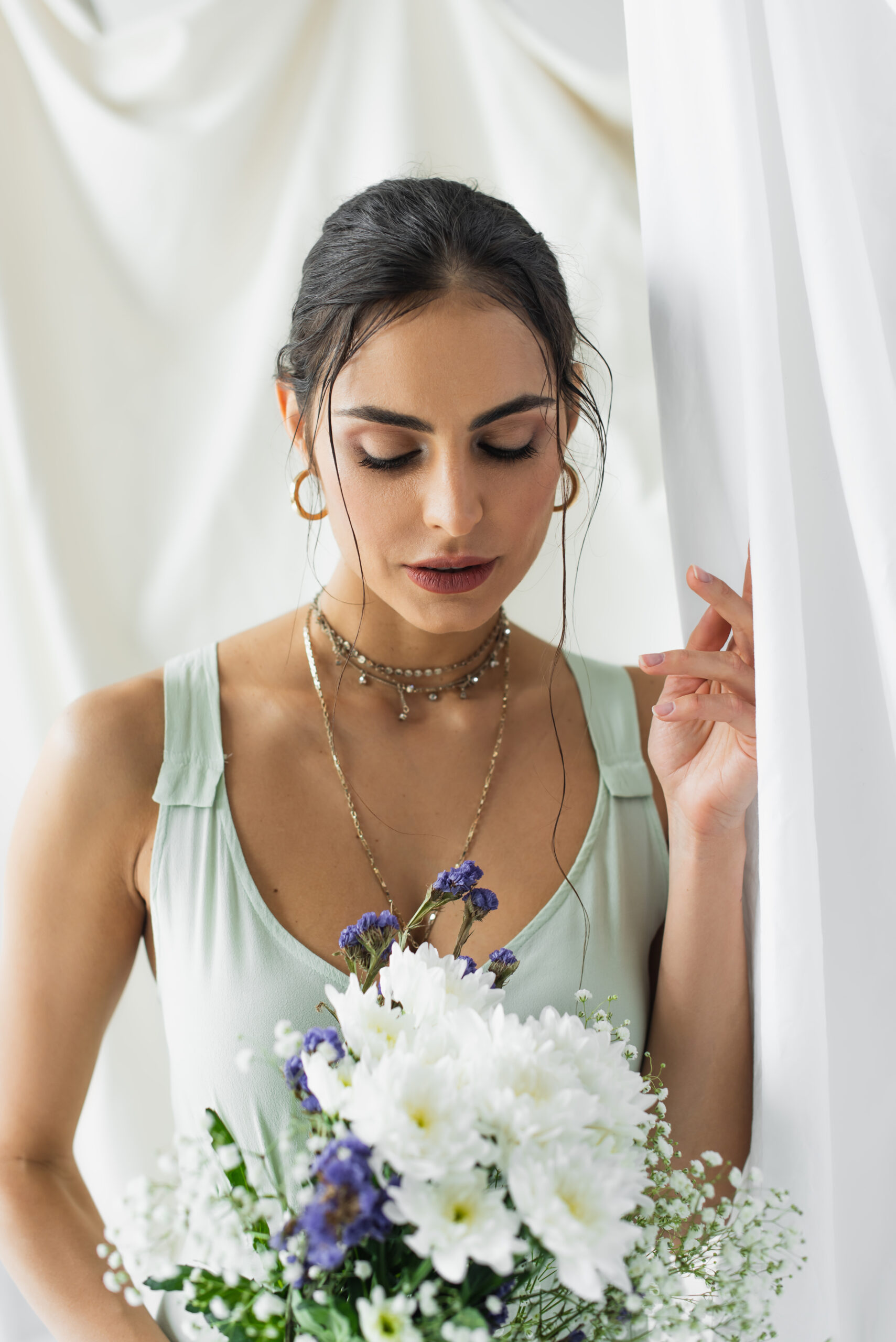 woman in dress looking at bouquet of flowers on white